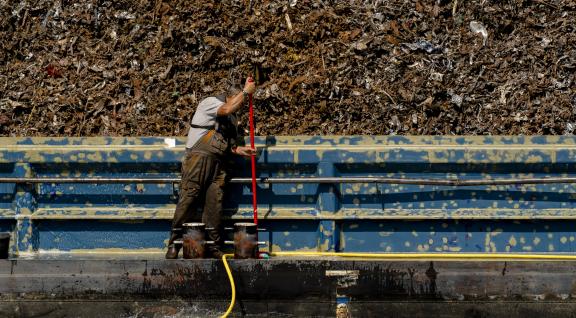 Afvalboot met vuilnisman aan het werk
